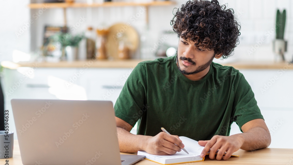 Man looking at computer while writing