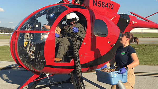 Wildlife Services employees in a small helicopter.
