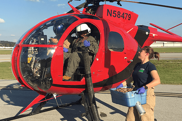 Wildlife Services employees in a small helicopter.