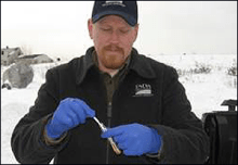 Wildlife Services employee holding a test tube collecting samples