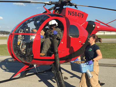 Wildlife Services employees in a small helicopter.